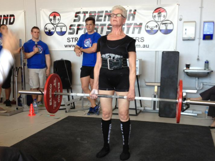 Masters lifter finishing a deadlift at a competition